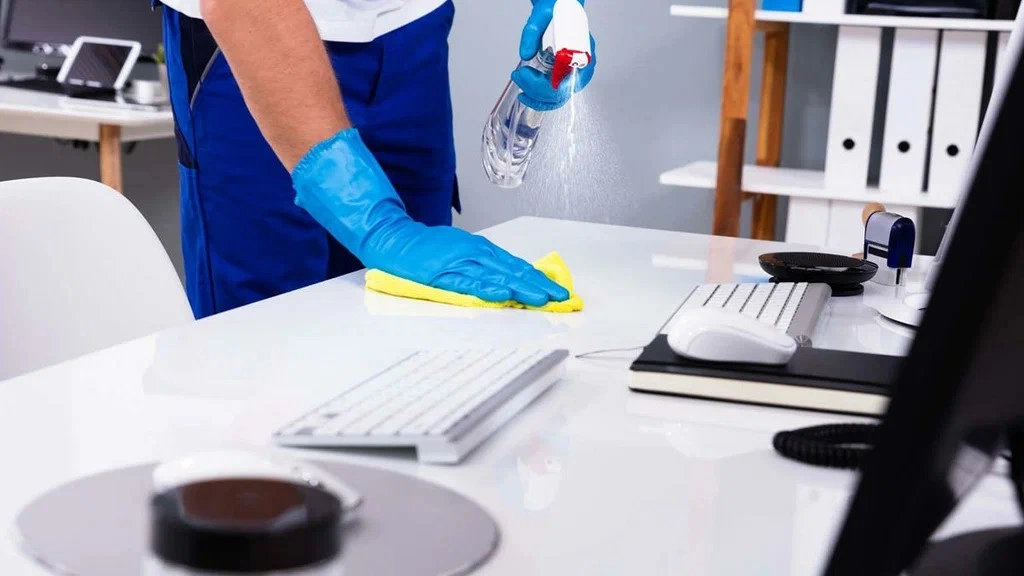 A woman From Brye A+ Team sanitize Bank Desk.