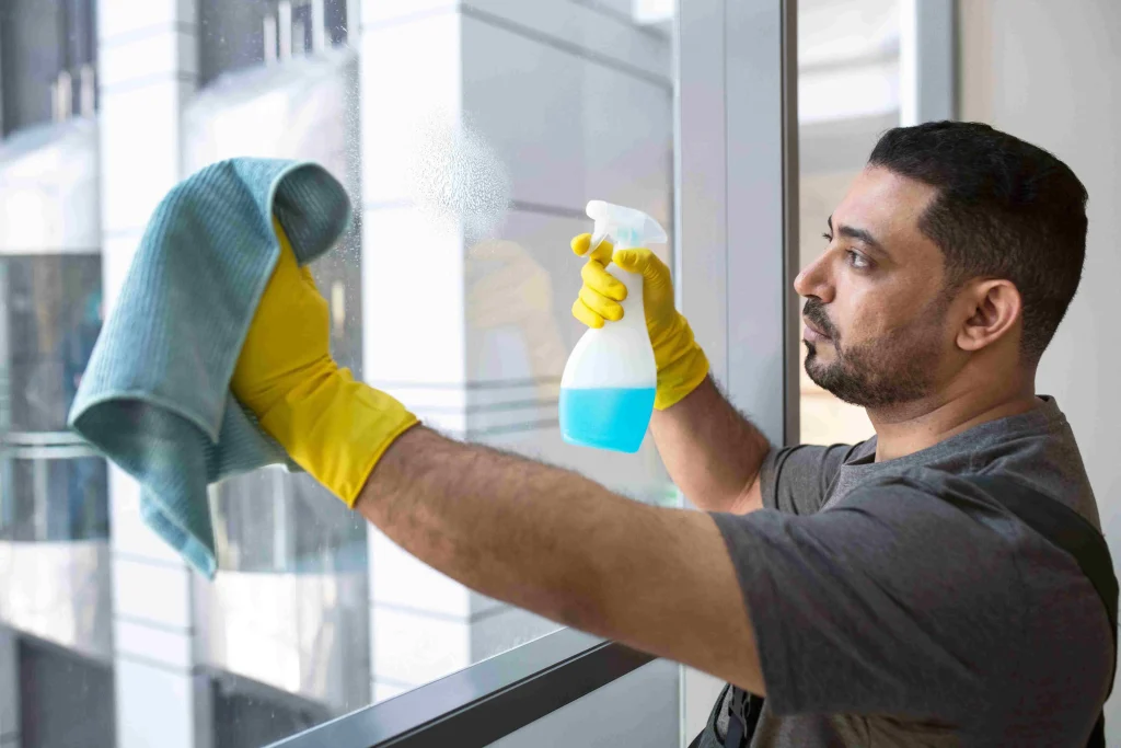 Man Post-Renovation window cleaning with spray and cloth, for a clear, streak-free finish in a modern office setting