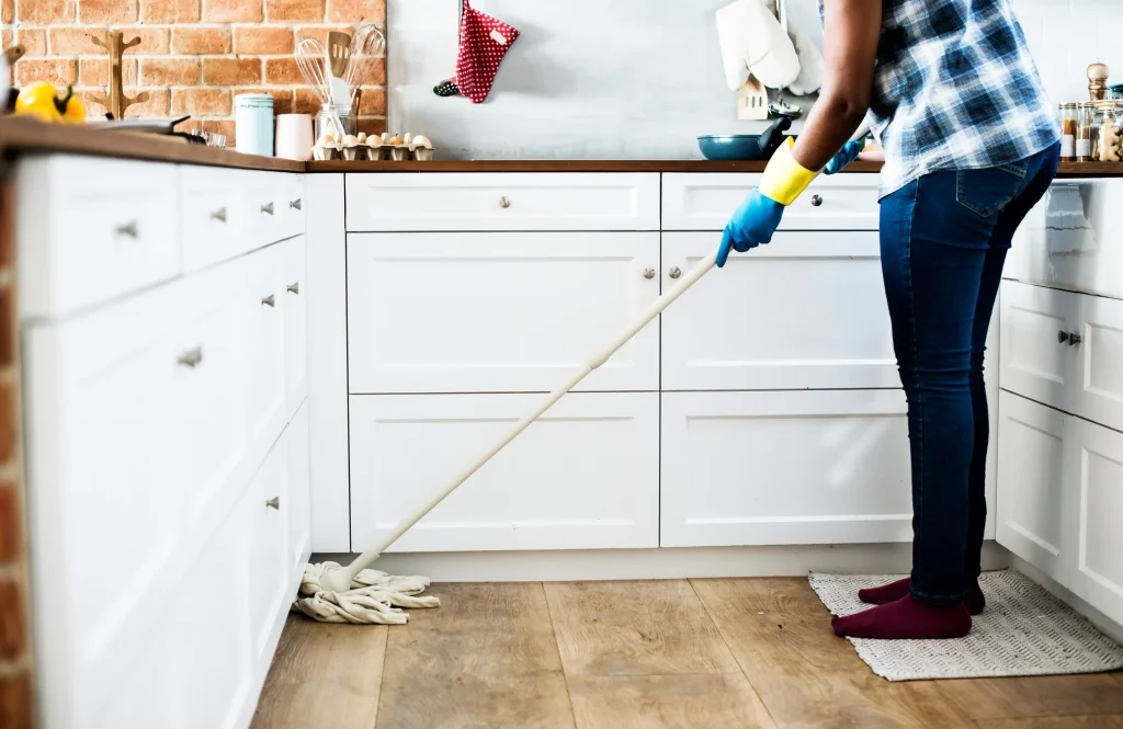 Man carrying out post-renovation cleanup, cleaning kitchen surfaces and floors after renovation