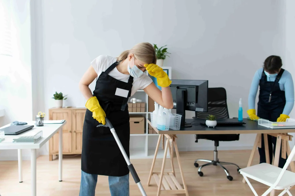 Man and woman mopping office floor during professional office cleaning in modern workspace environment