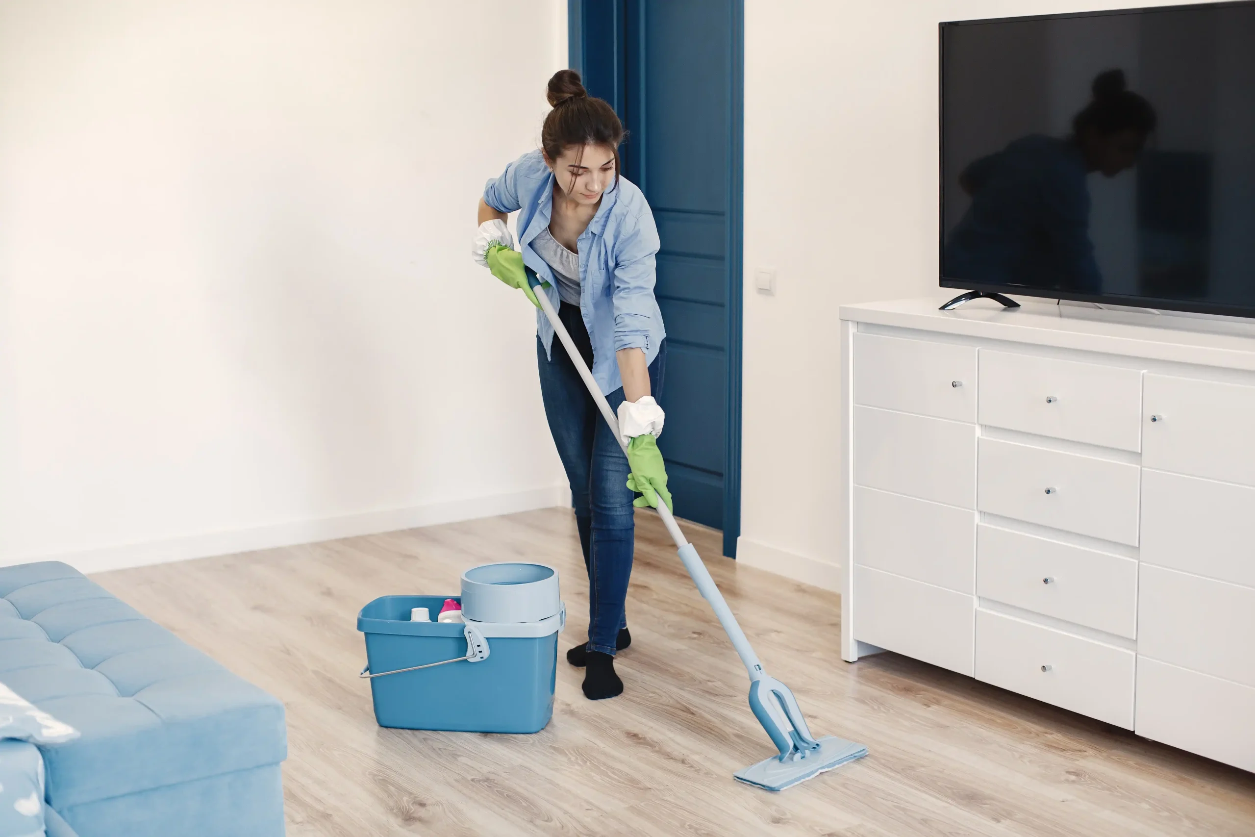 Woman mopping floor in a clean, empty apartment during move-in cleaning.