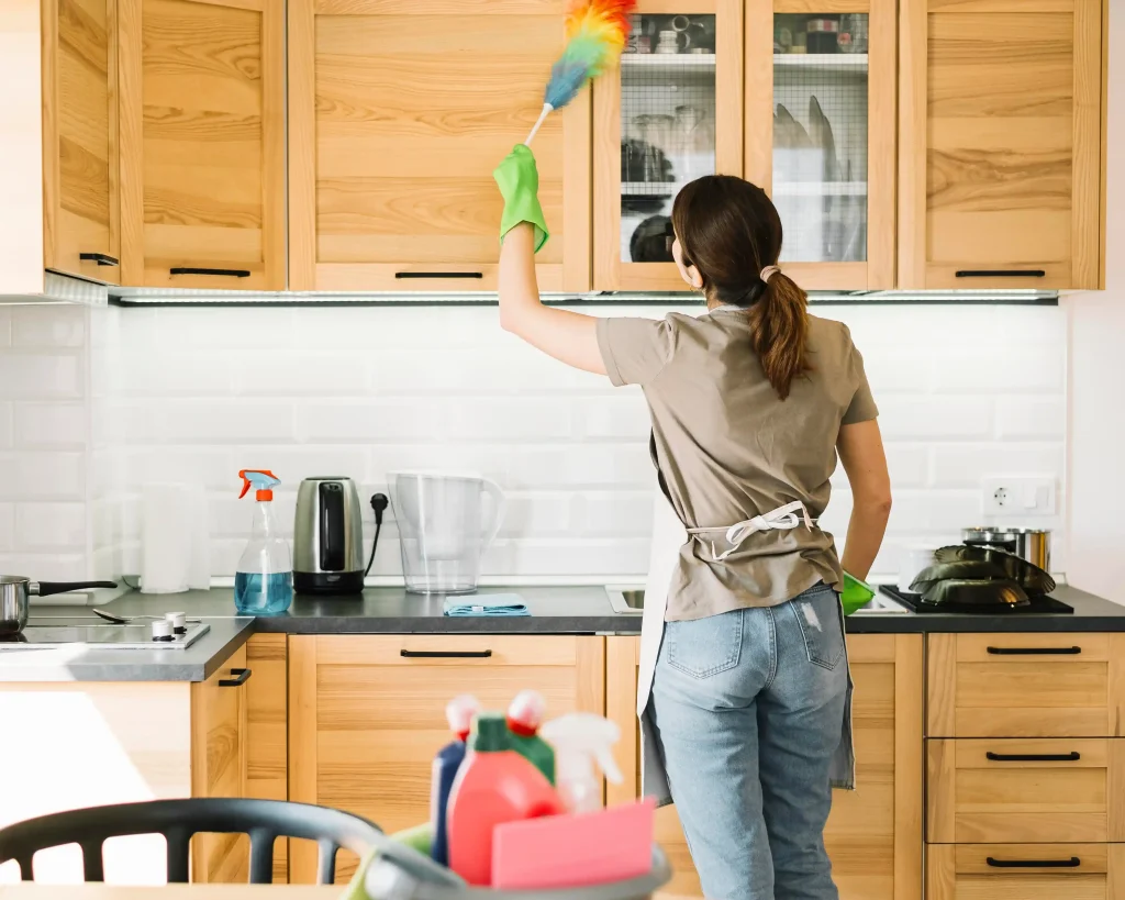Move-out cleaning dusting shelves with duster in kitchen during cleaning process
