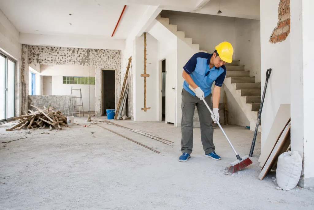 Worker sweeping debris during post-construction cleaning in a renovated building.