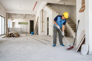 Worker sweeping debris during post-construction cleaning in a renovated building.