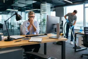 Employee feeling unwell at work while professional office cleaning in flu season helps maintain a healthier workspace.